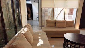 Ein modernes Wohnzimmer mit einer Couch, einem runden Tisch und Blick durch eine Glastür.