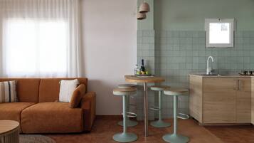 Ein Wohnzimmer mit einer Couch, einem runden Couchtisch und einer Küchenzeile mit Spüle und Schränken.
