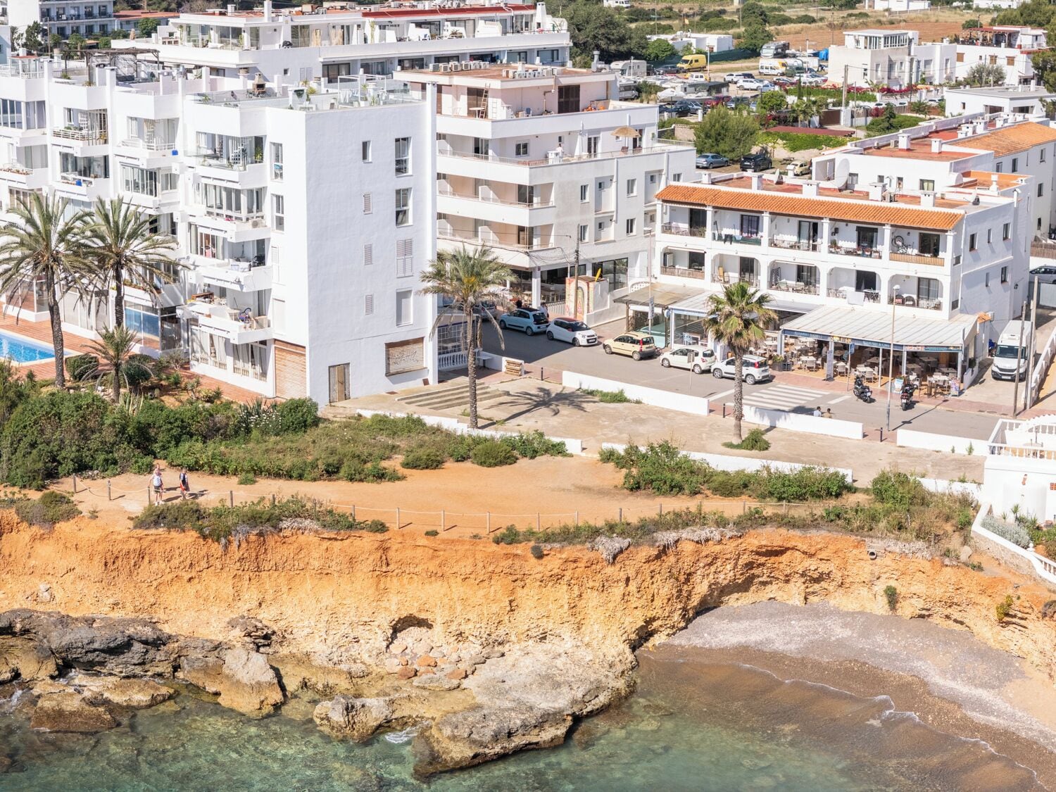 Eine Küstenstadt mit modernen Gebäuden, einem Strand und klarem Wasser.