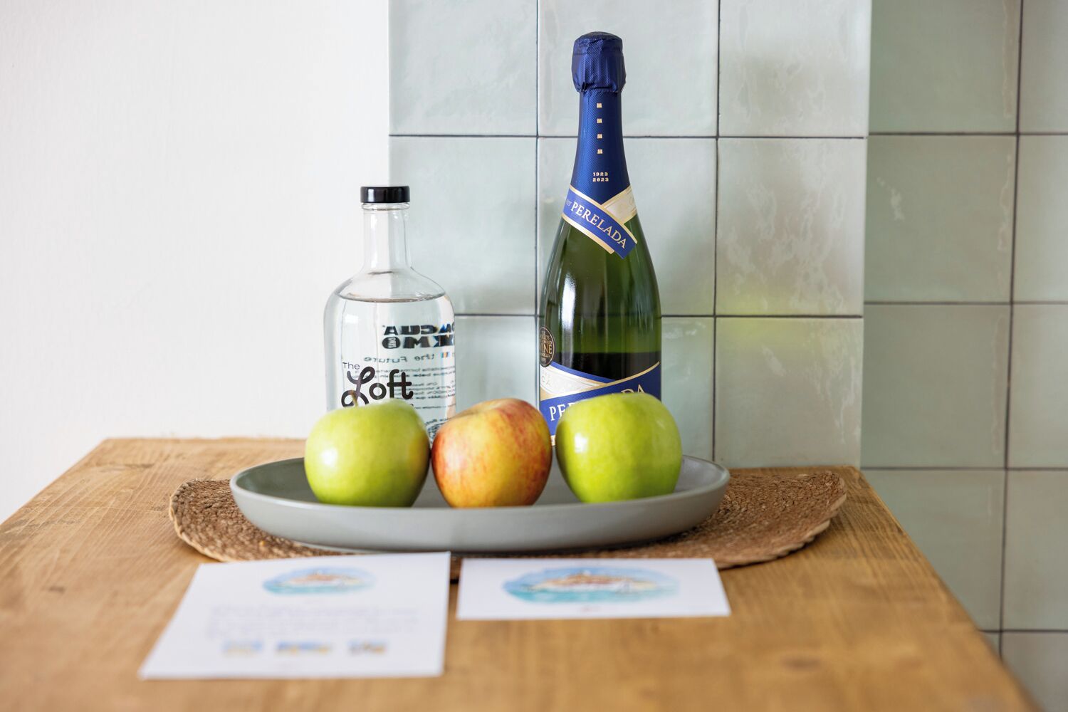 Une assiette avec trois pommes et une bouteille de champagne sur une table en bois.