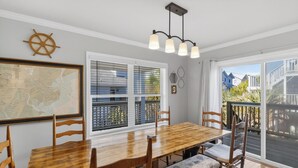 Un comedor con una mesa y sillas de madera, un mapa en la pared, una ventana con persianas y vistas a la terraza exterior.