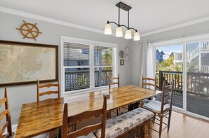 Ein Essbereich mit Holztisch und -stühlen, einer Karte an der Wand, einem Fenster mit Jalousien und Blick auf die Terrasse.