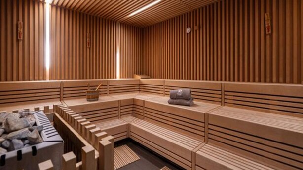 Uma sauna com bancos de madeira e uma bacia de pedra.