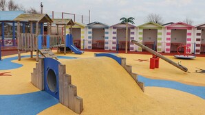 Ein Spielplatz mit Rutsche, Klettergerüsten und Sandkasten.
