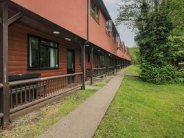 A row of log cabin-style buildings with a covered walkway and outdoor seating.