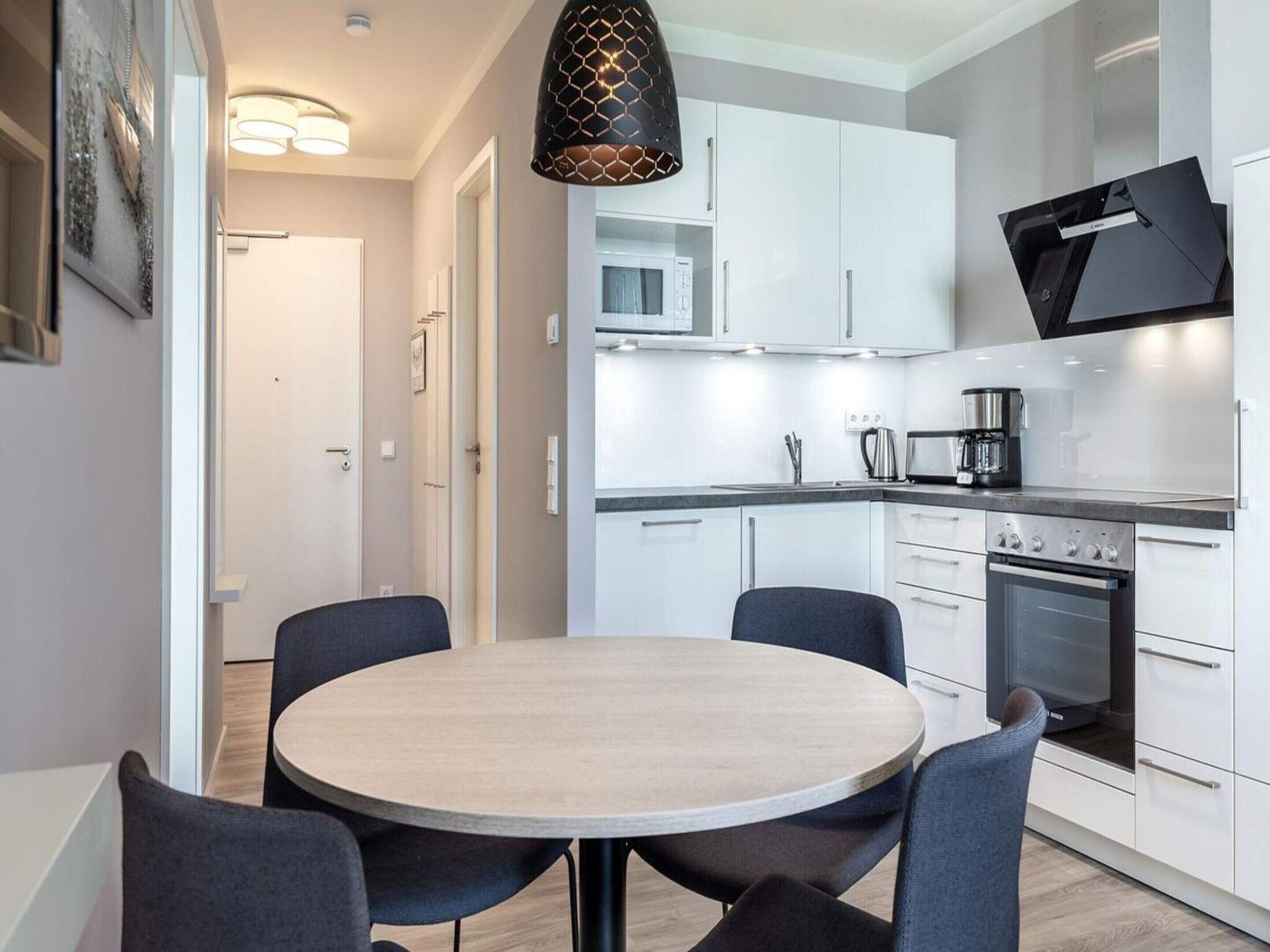 A modern kitchen with white cabinets, a Bosch oven, and a round dining table with chairs.