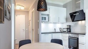 A modern kitchen with white cabinets, a Bosch oven, and a round dining table with chairs. - 4 Star Holiday Home in Travemunde (Lübeck)