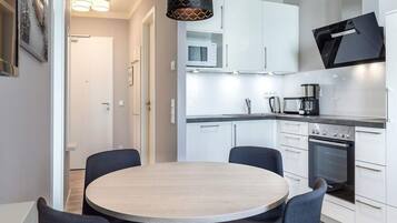 A modern kitchen with white cabinets, a Bosch oven, and a round dining table with chairs.