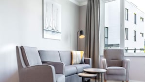 A modern living room with a grey sofa, a grey armchair, a round coffee table, and a floor lamp. - 4 Star Holiday Home in Travemunde (Lübeck)