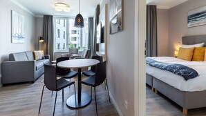 A modern hotel room with a bed, a seating area with a table and chairs, a large window, and artwork on the walls. - 4 Star Holiday Home in Travemunde (Lübeck)