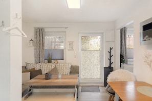 Ein modernes Wohnzimmer mit Sofa, Esstisch und einer Schiebetür zum Balkon.