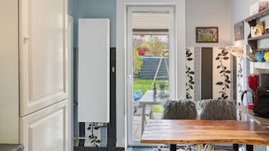 Eine Küche mit Essbereich, einem Kühlschrank, einem Tisch, Stühlen und Blick auf den Garten.