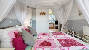 Ein Schlafzimmer mit Himmelbett, Nachttisch und Blick auf einen Essbereich.