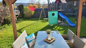 Ein Garten mit Spielbereich, einem Tisch und Gartenmöbeln.