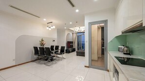 Uma cozinha moderna com fogão embutido, sala de jantar com cadeiras e mesa, e sala de estar com sofá e televisão.