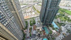 Um edifício alto com design moderno, com piscina no terraço e áreas ajardinadas.