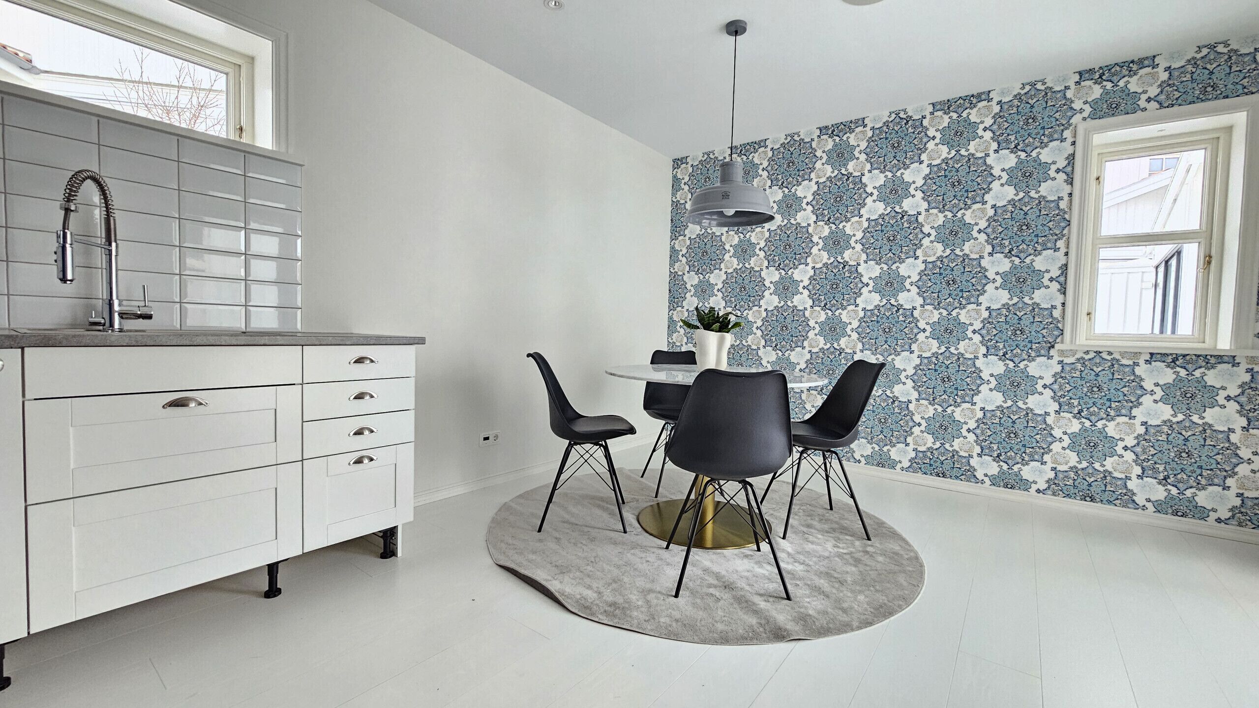 Una cocina moderna con encimera blanca, un fregadero y un comedor con mesa y sillas.