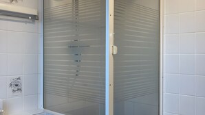Un bagno moderno con cabina doccia in vetro, piastrelle bianche e portasciugamani.