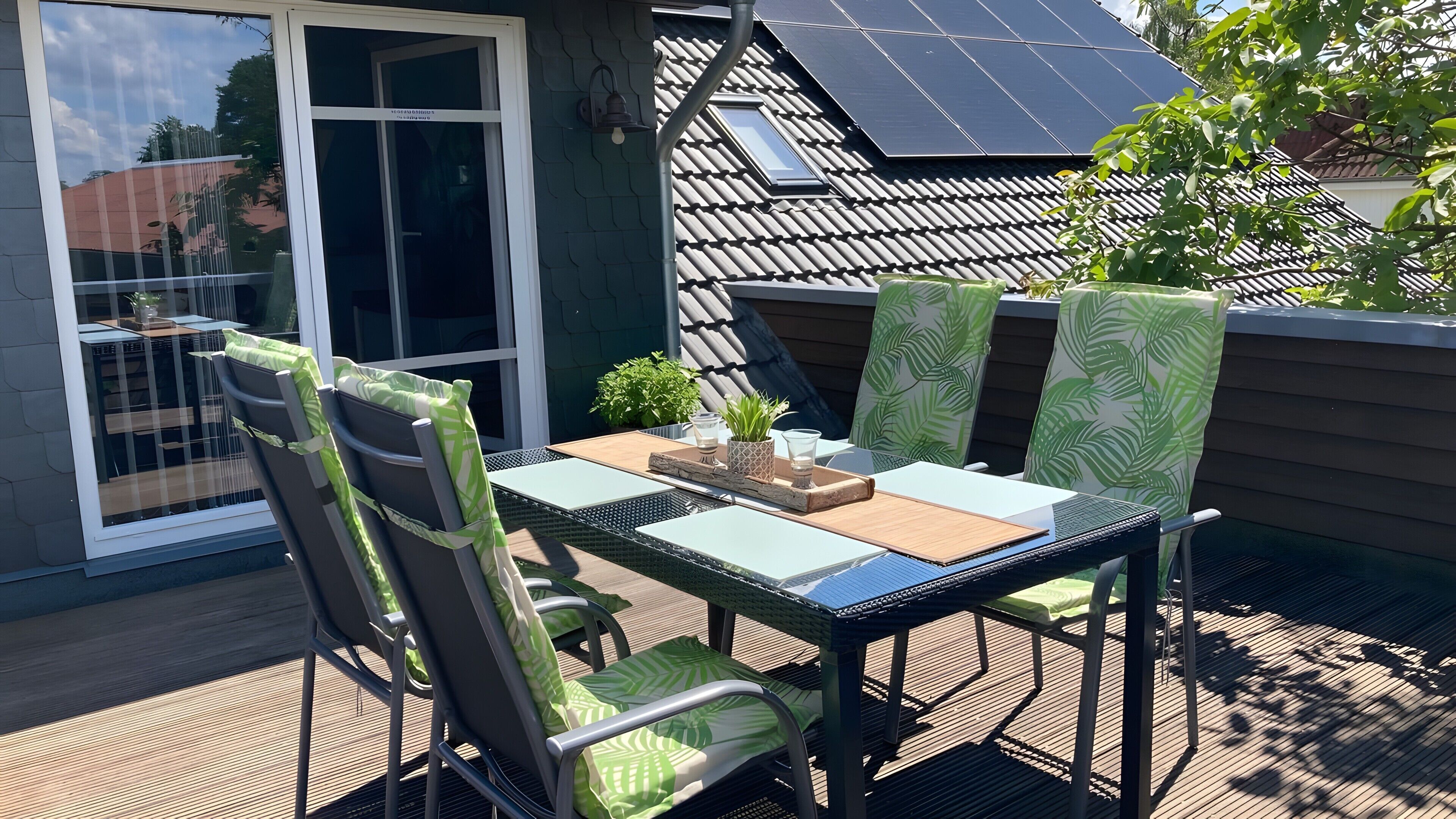 Un patio al aire libre con una mesa, sillas y una planta en maceta.