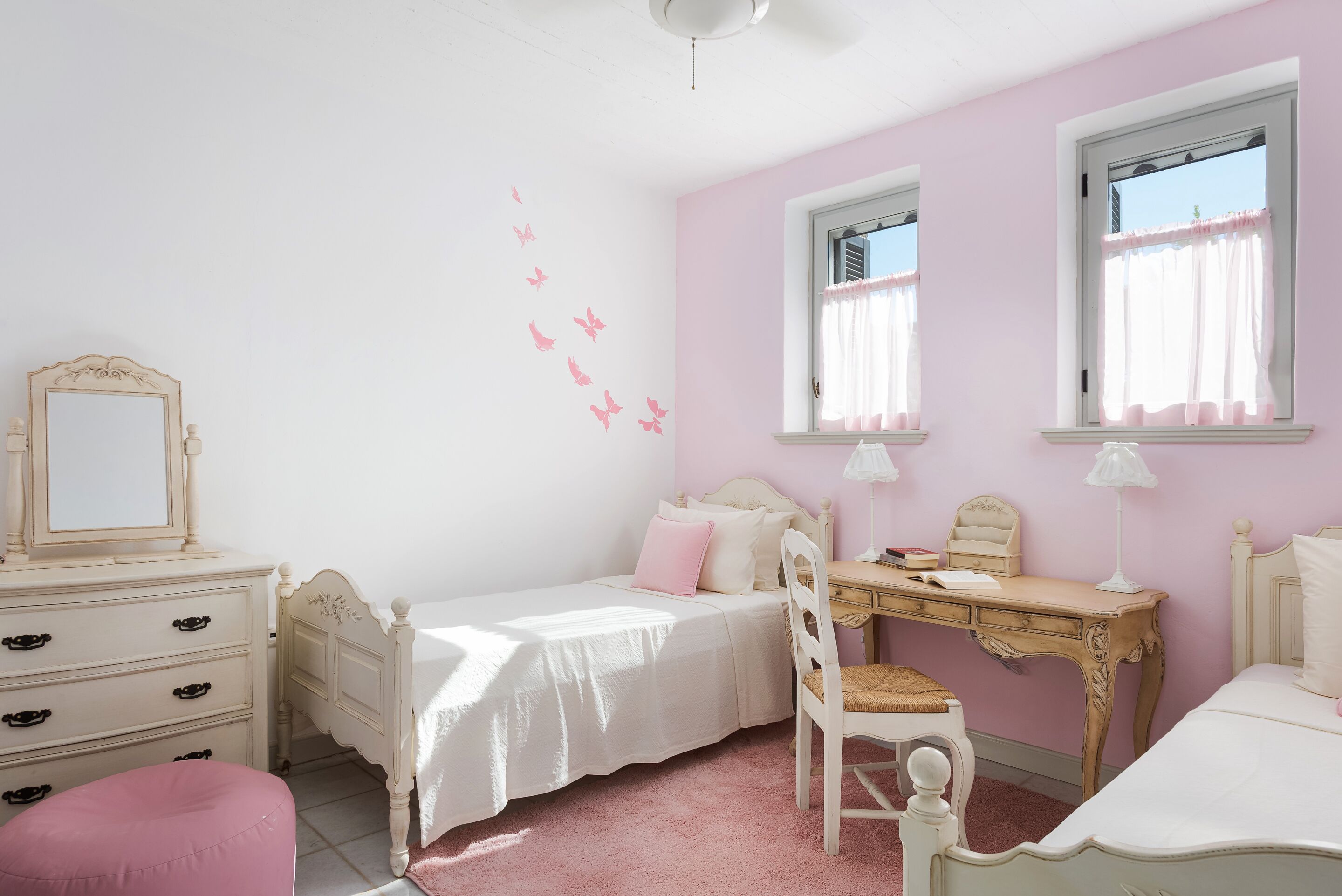 Un dormitorio con una cama individual, un escritorio, una silla, un aparador y un espejo.