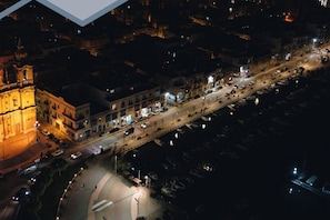 Una vista aerea di una strada cittadina di notte, con edifici, una chiesa importante e una rotonda.