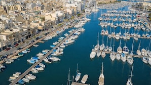 A marina filled with boats, a cityscape with buildings, and a clear blue sky. - Stylish 2BR Retreat w/ Balcony & Fast WiFi (Msida)