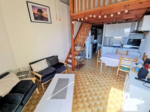 Ein gemütlicher Wohnbereich mit einer Couch, einem Esstisch mit Stühlen, einer Küchenzeile und einer Treppe.