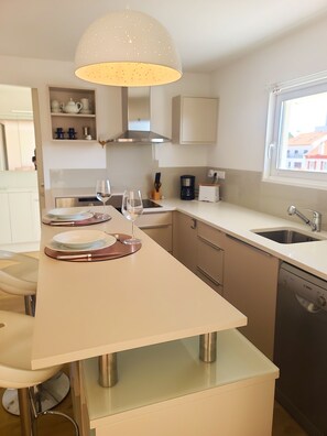 A modern kitchen with a central island, a Bosch dishwasher, a window with a view, and a pendant light.
