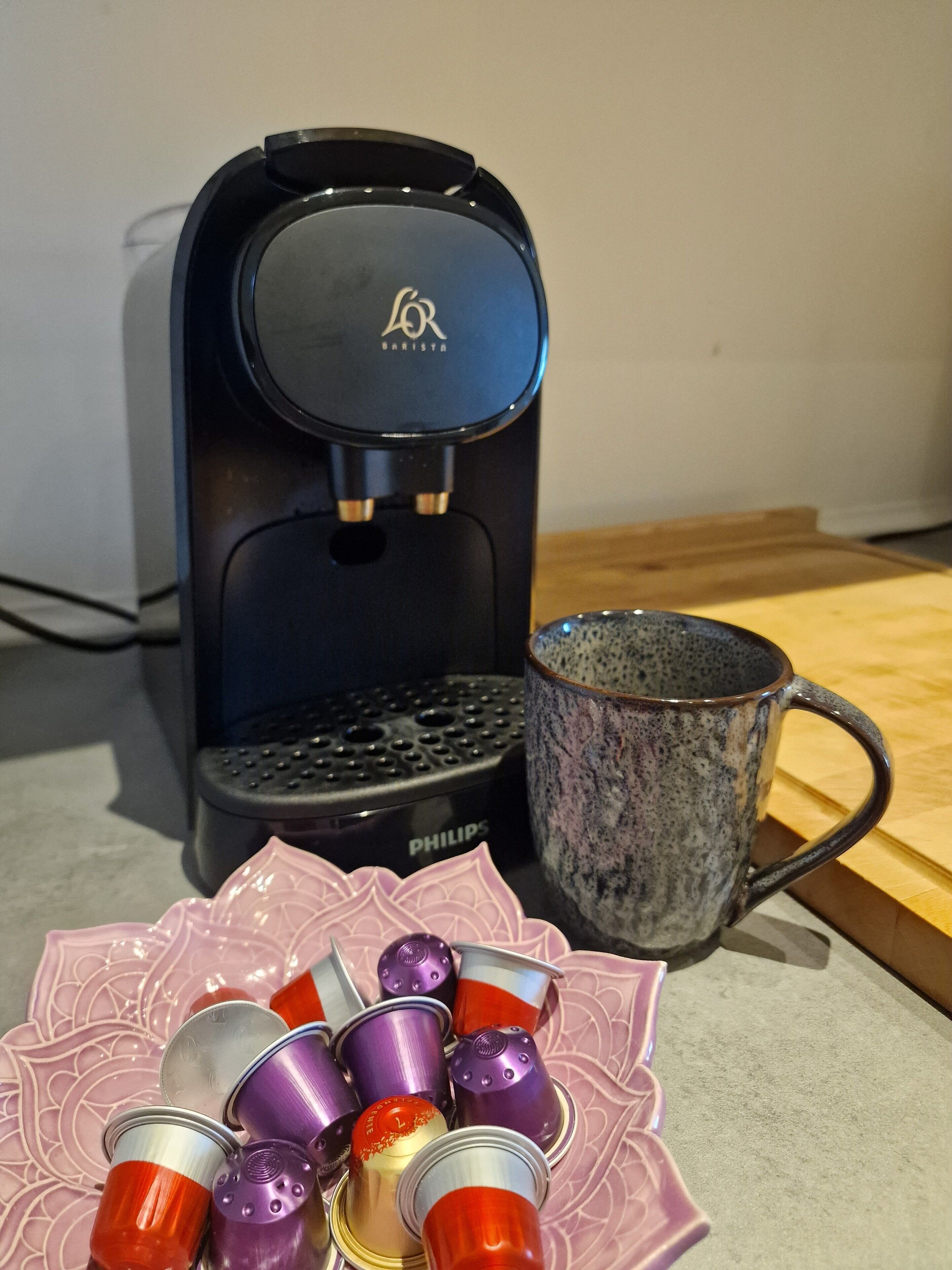Une machine à café, une tasse et une assiette avec des tasses aux couleurs vives.