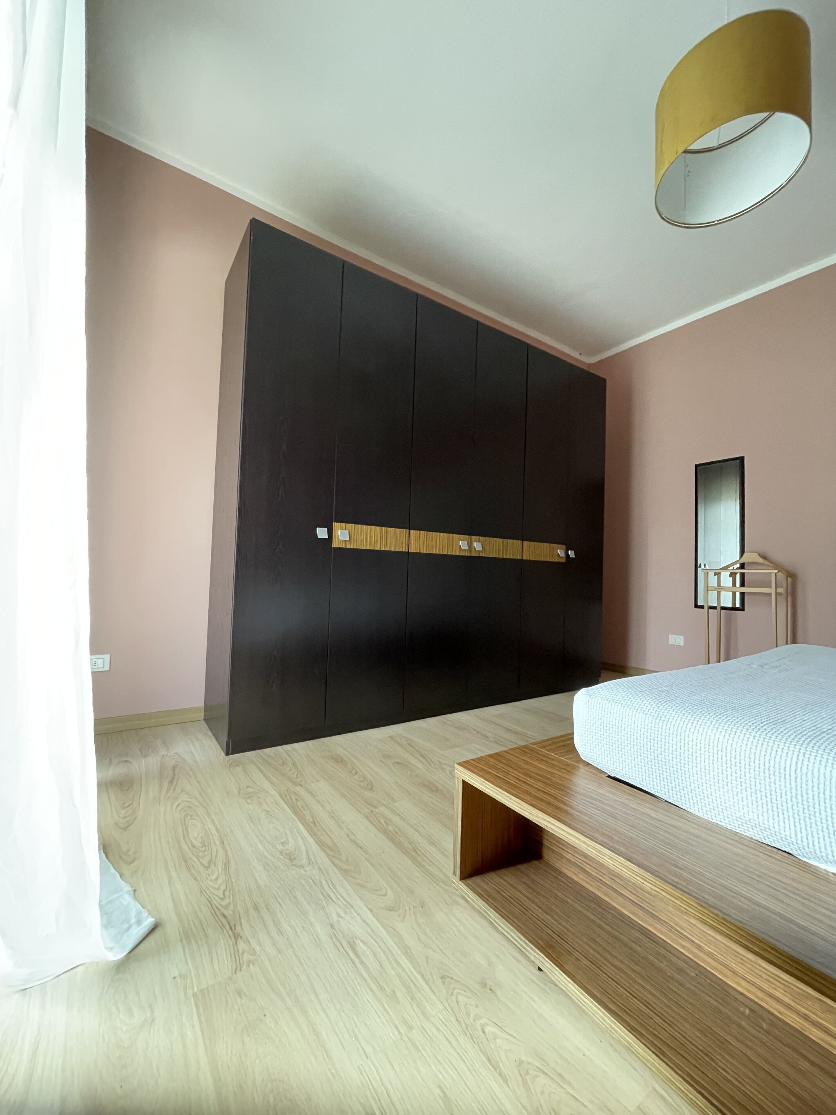 Ein Schlafzimmer mit einem Bett, einer Holzbank, einem Kleiderschrank und einem Spiegel.