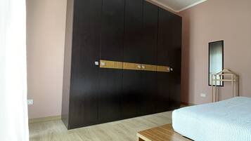 Ein Schlafzimmer mit einem Bett, einer Holzbank, einem Kleiderschrank und einem Spiegel.
