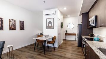 A modern kitchen with wooden flooring, a dining area with a marble table, and a kitchen island.