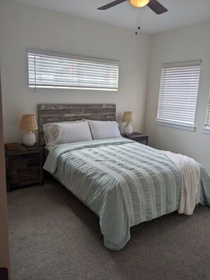 A bedroom with a bed, two nightstands, a ceiling fan, and two windows with blinds. - Cozy Colorado Escape w/ Mountain Views (Colorado Springs)