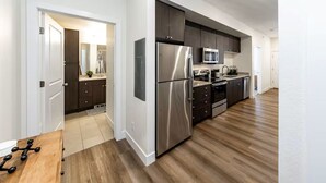 Une cuisine moderne dotée d’appareils électroménagers en acier inoxydable, de meubles de rangement aux couleurs sombres et d’un plancher en bois.