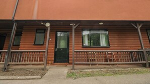 Ein zweistöckiges Gebäude mit flachem Dach, einer Haustür und einer kleinen Veranda mit Geländer.