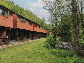 A building with a red exterior, multiple windows, and a covered outdoor area with benches. - Cabin No. 9 - Salt and Fern Cabins (Port Talbot)