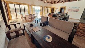 A spacious living area with a sofa, a dining table, and a kitchen area with a counter. - Villa Ryad Ibou (Aguerd)