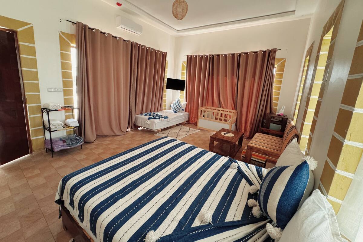 Quarto com uma cama, uma cadeira de madeira, uma mesa pequena e um berço.