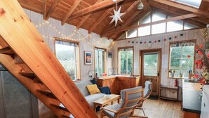 A wooden interior with a staircase, a sofa, a dining table, and a kitchen area. - Cosy Eco Cabin (Newport)