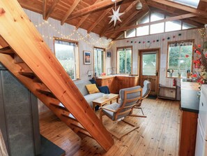 A wooden interior with a staircase, a sofa, a dining table, and a kitchen area. - Cosy Eco Cabin (Newport)