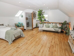 Une chambre à coucher comprenant un lit, un canapé, une petite table, une plante en pot et un escalier menant à un niveau supérieur.