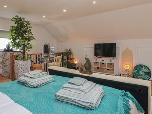 A hotel room with a bed, a TV, a plant, and a shelf with decorative items. - The Retreat (Goole)