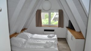 A bedroom with a bed, a window, a television, and a small kitchenette. - Holiday Home 'Meinhaus-damp' with Terrace, Garden and Wi-Fi (Damp)