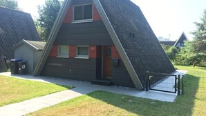A modern, triangular-shaped building with a sloped roof, a small entrance, and a visible window. - Holiday Home 'Meinhaus-damp' with Terrace, Garden and Wi-Fi (Damp)