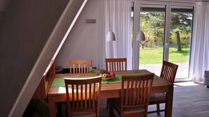 A dining area with a table, chairs, and a view of a garden through a sliding glass door. - Holiday Home 'Meinhaus-damp' with Terrace, Garden and Wi-Fi (Damp)