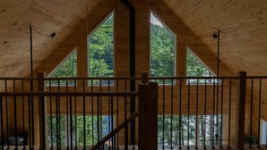 Un intérieur en bois avec un plafond haut, des fenêtres triangulaires et une balustrade.
