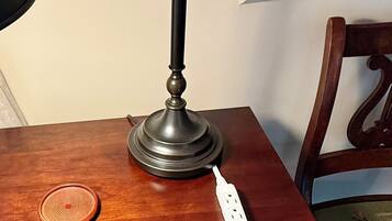 Een houten tafel met een bureaulamp, een stekkerdoos en een onderzetter.