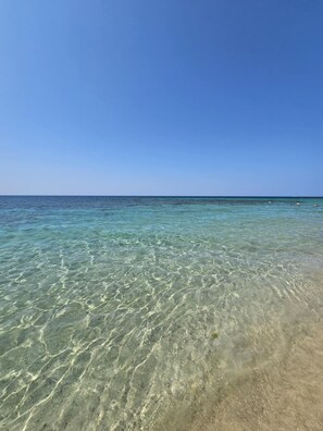 Visão clara de uma praia com águas rasas e horizonte distante.