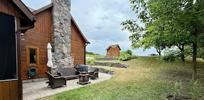A wooden cabin with stone pillars, outdoor seating, and a view of the landscape.
