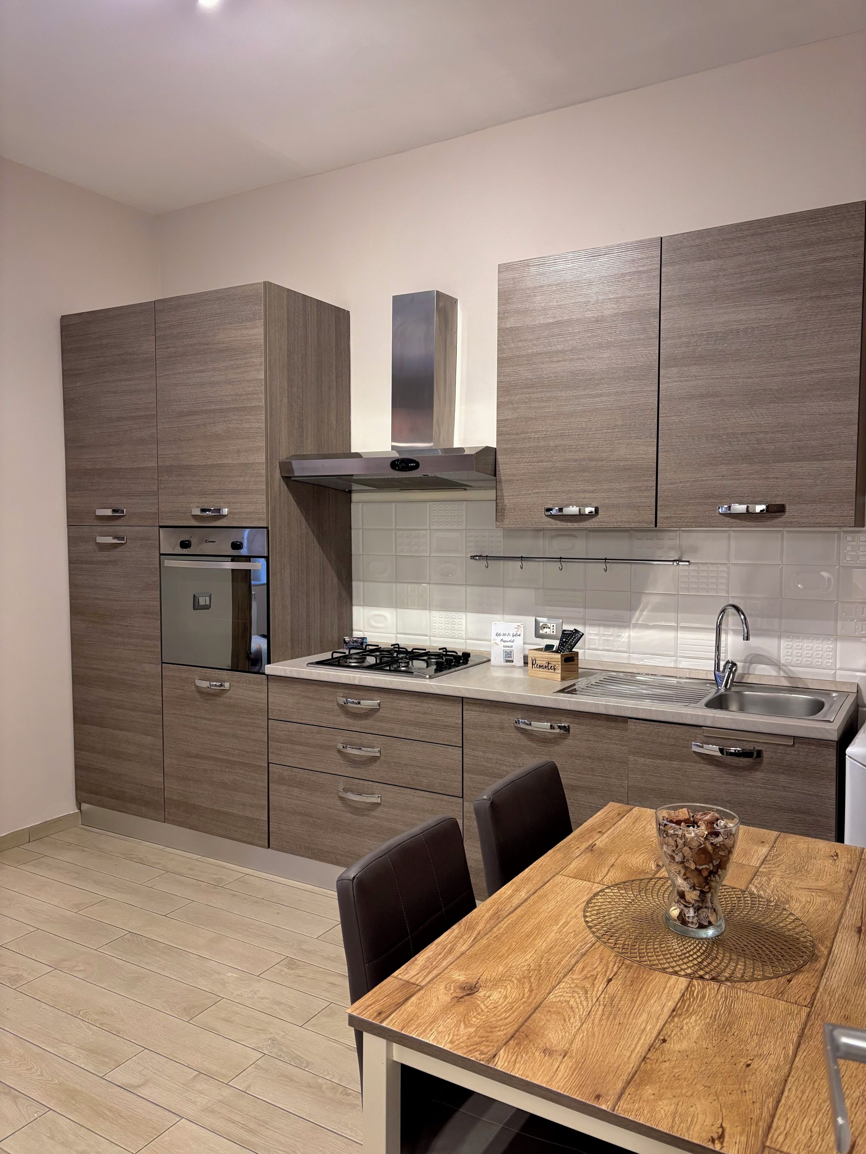 A modern kitchen with wooden cabinets, a gas stove, a built-in oven, and a dining area with a wooden table and chairs.